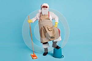 Cleaning hero. Photo of pensioner old man grey beard hold mop leg bucket self-assured wear santa x-mas costume apron