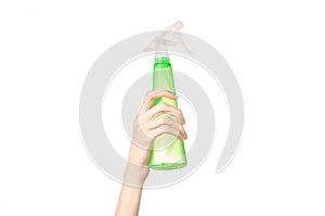 Cleaning the house and cleaner theme: man's hand holding a green spray bottle for cleaning isolated on a white background