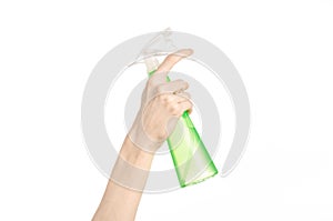 Cleaning the house and cleaner theme: man's hand holding a green spray bottle for cleaning isolated on a white background