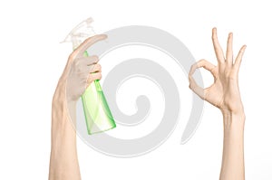 Cleaning the house and cleaner theme: man's hand holding a green spray bottle for cleaning isolated on a white background
