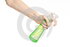 Cleaning the house and cleaner theme: man's hand holding a green spray bottle for cleaning isolated on a white background