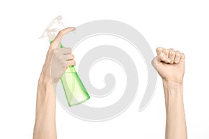 Cleaning the house and cleaner theme: man's hand holding a green spray bottle for cleaning isolated on a white background