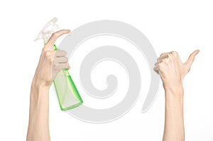 Cleaning the house and cleaner theme: man's hand holding a green spray bottle for cleaning isolated on a white background