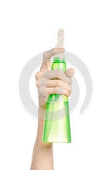 Cleaning the house and cleaner theme: man's hand holding a green spray bottle for cleaning isolated on a white background