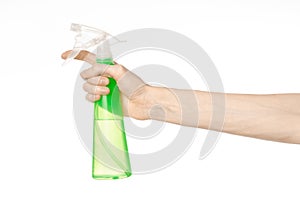 Cleaning the house and cleaner theme: man's hand holding a green spray bottle for cleaning isolated on a white background