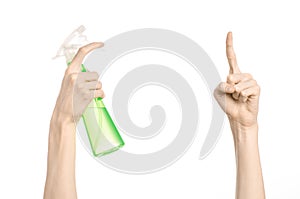 Cleaning the house and cleaner theme: man's hand holding a green spray bottle for cleaning isolated on a white background