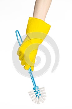 Cleaning the house and cleaning the toilet: human hand holding a blue toilet brush in yellow protective gloves isolated on a white