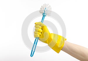 Cleaning the house and cleaning the toilet: human hand holding a blue toilet brush in yellow protective gloves isolated on a white