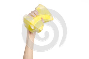 Cleaning the house and sanitation topic: Hand holding a yellow sponge wet with foam isolated on a white background in studio