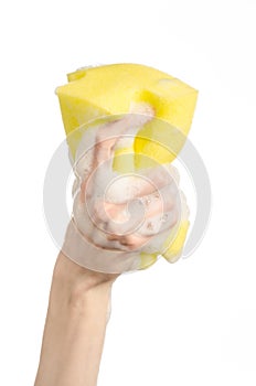 Cleaning the house and sanitation topic: Hand holding a yellow sponge wet with foam isolated on a white background in studio