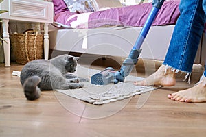 Cleaning house with vacuum cleaner, female with pet cat