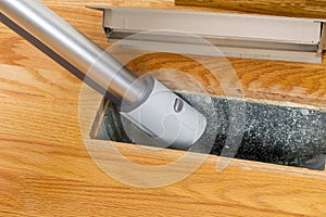 Cleaning inside heating floor vent with Vacuum Cleaner photo