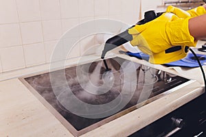 Cleaning kitchen hob with a steam cleaner.