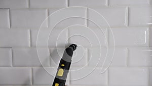 Cleaning kitchen tiles with steam. A woman washes ceramic tiles in a bathroom with a steam generator. Steam cleaning