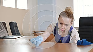 A cleaning lady cleans office desk.