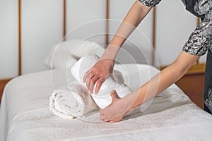 A cleaning lady folds a towel on a massage bed