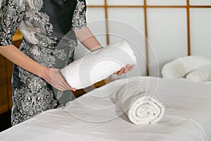 A cleaning lady folds a towel on a massage bed