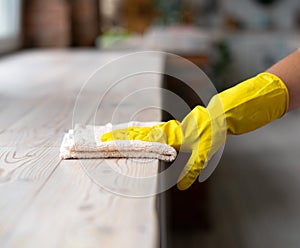 A Cleaning lady with gloves wipes dust from furniture with a cloth