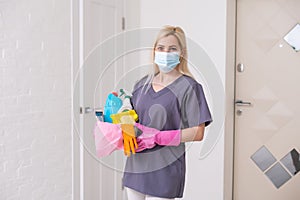 A cleaning lady with a mask on her face cleans the hallway