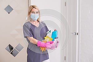 A cleaning lady with a mask on her face cleans the hallway