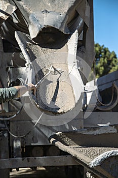 Worker cleaning the last remains of concrete from the mouth of the truck photo