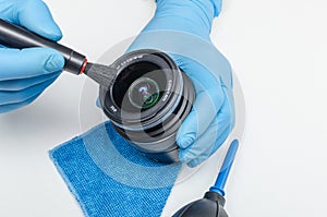 Cleaning the lens of a digital camera and the front lens of contamination with a brush. Maintenance of digital cameras photo