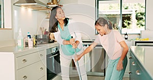 Cleaning, mom and girl dance in the kitchen with a broom, sweeping and or fun housework with music in family home. Kid