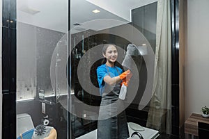 Cleaning online service. yong woman housekeeper cleaning bathroom mirror with cloth. House cleaning service concept