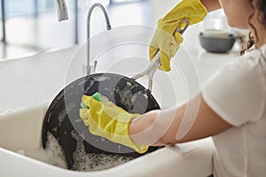 Cleaning pan, washing and hygiene hands with soap and water in the kitchen sink in home. Zoom of a female hand and