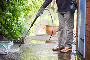 Cleaning patio paving with a high pressure washer the man is using the water to clean the garden path