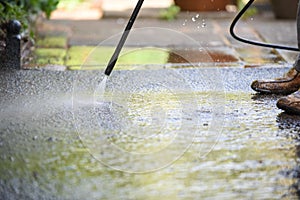 Cleaning patio paving with a high pressure washer the man is using the water to clean the garden path