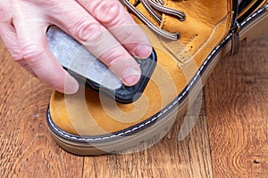 Cleaning and polishing of brown nubuck winter boots, shoe care product. Man cleaning brown fashionable nubuck shoes