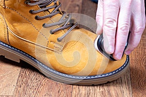 Cleaning and polishing of brown nubuck winter boots, shoe care product. Man cleaning brown fashionable nubuck shoes