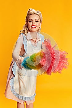 Cleaning. Portrait of beautiful young blonde woman with stylish hairstyle posing with pipidastre against yellow studio