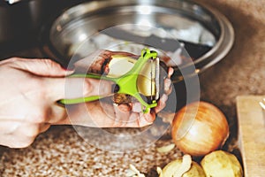 Cleaning potatoes. Woman`s hands clean potatoes special tool