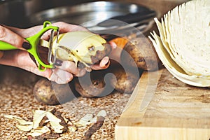 Cleaning potatoes. Woman`s hands clean potatoes special tool