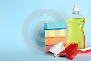 Cleaning product and tools on light blue background, space for text. Dish washing supplies
