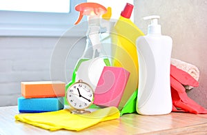 Cleaning service background with household chemicals and clock. Concept of cleanliness and freshness in the house