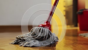 Cleaning service. Cleaner washes parquet with wet mop. Close-up of mopping floor. Follow shot. Low angle view