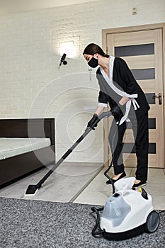 Cleaning service company employee removing dirt from carpet in flat with professional steam cleaner equipment