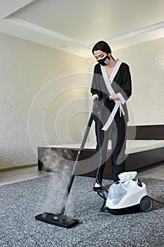 Cleaning service company employee removing dirt from carpet in flat with professional steam cleaner equipment