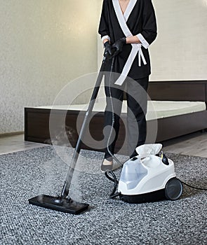 Cleaning service company employee removing dirt from carpet in flat with professional steam cleaner equipment