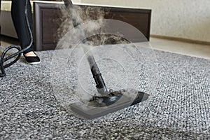 Cleaning service company employee removing dirt from carpet in flat with professional steam cleaner equipment close up