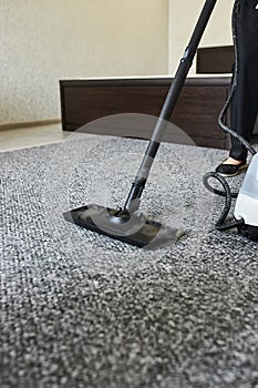 Cleaning service company employee removing dirt from carpet in flat with professional steam cleaner equipment close up