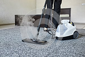 Cleaning service company employee removing dirt from carpet in flat with professional steam cleaner equipment close up