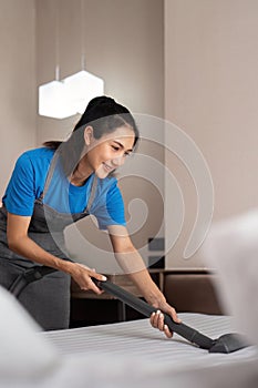 Cleaning service employee removing dirt from with professional equipment. Female housekeeper cleaning the mattress on
