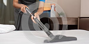 Cleaning service employee removing dirt from with professional equipment. Female housekeeper cleaning the mattress on