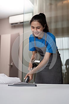 Cleaning service employee removing dirt from with professional equipment. Female housekeeper cleaning the mattress on