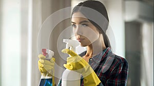 Cleaning service lady holding sprays for glass window surface, sanitizing room