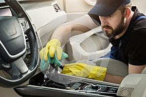 Cleaning service. Man in uniform and yellow gloves washes a car interior in a car wash